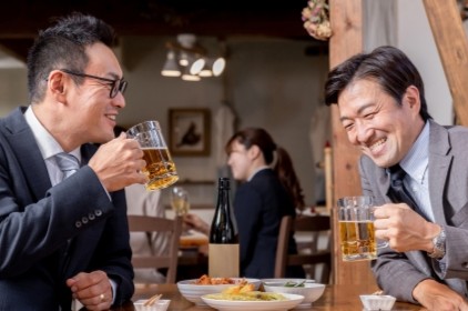 笑いながらビールを飲む