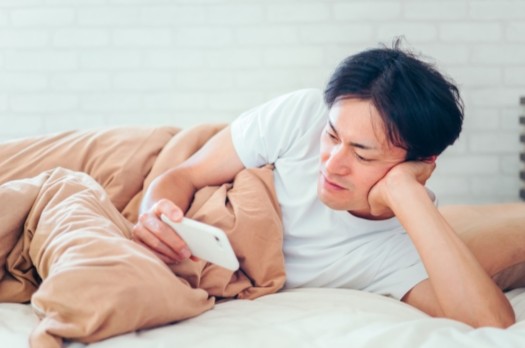 寝ながらスマホを観る男性
